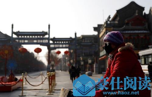一名女子戴着口罩骑车经过前门步行街